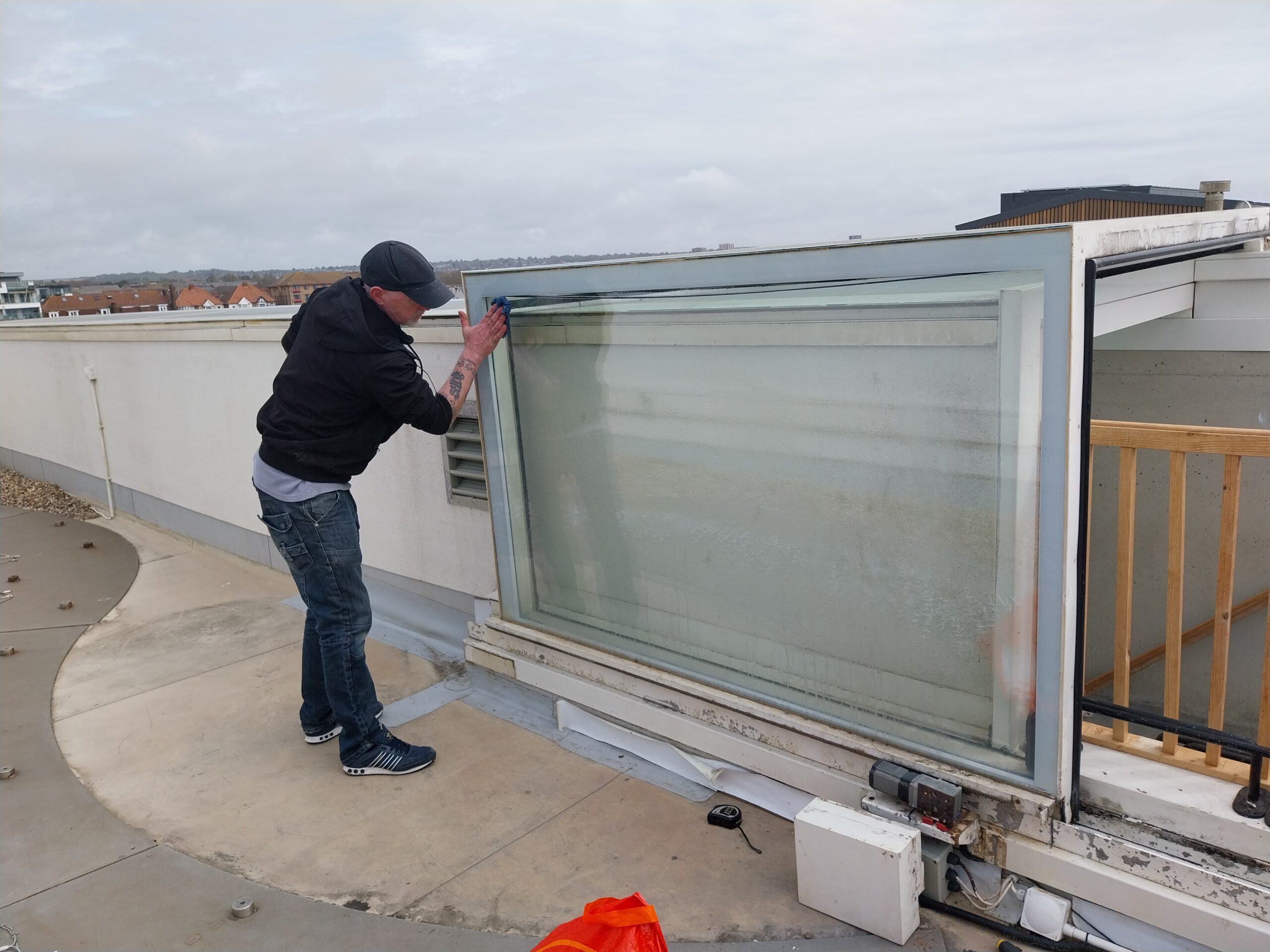 Person inspecting or installing a large glass window panel outdoors.