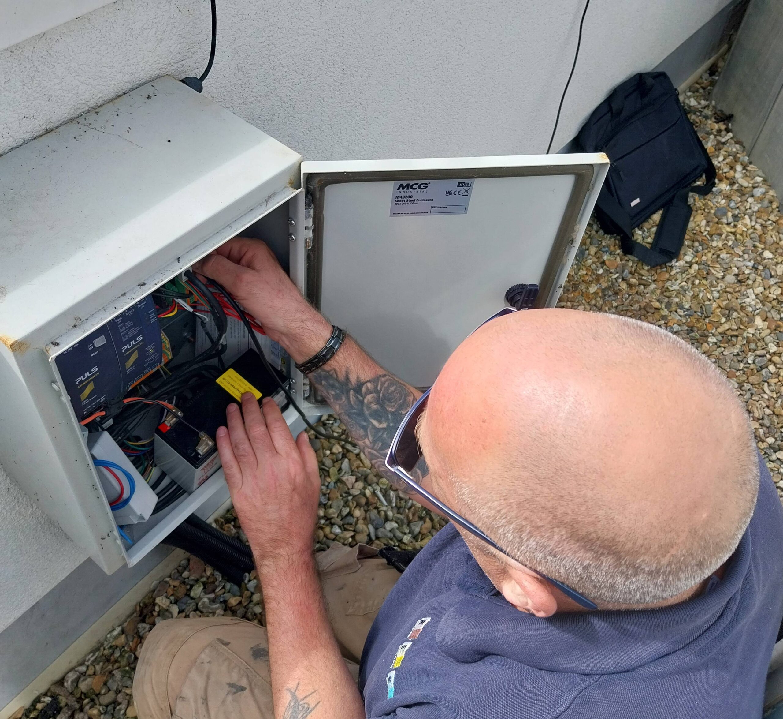 Technician repairing a outdoor electrical control box.